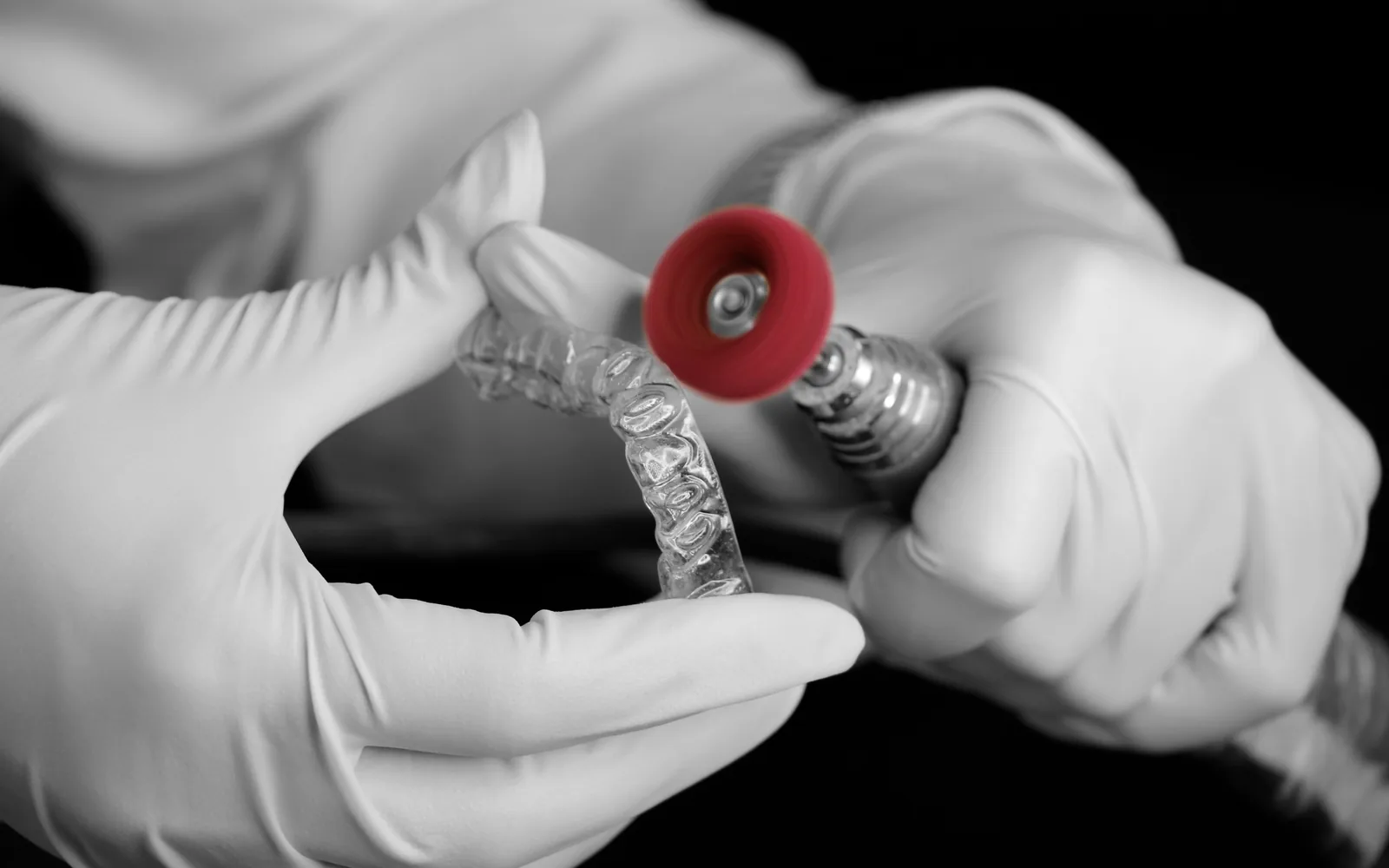 Clear orthodontic aligner being finished with a precision dental tool