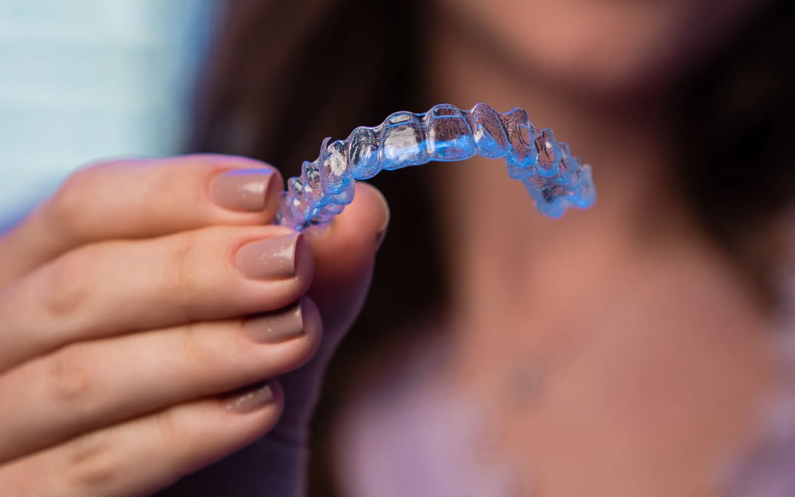 Person holding a clear orthodontic aligner
