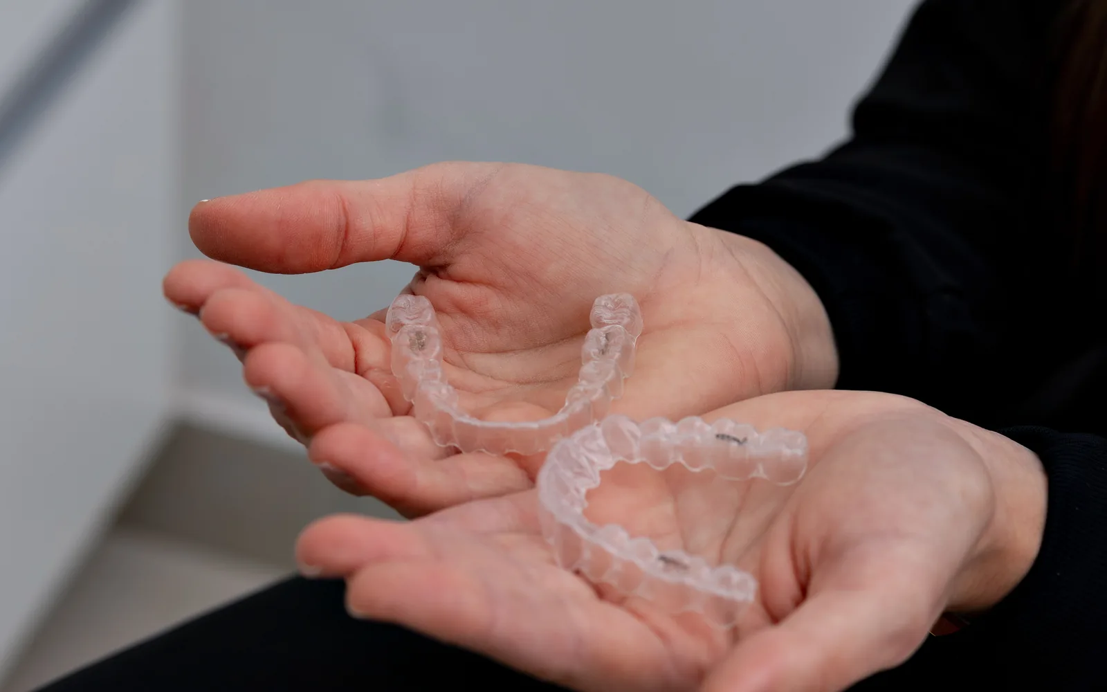 Hands holding upper and lower clear orthodontic aligners