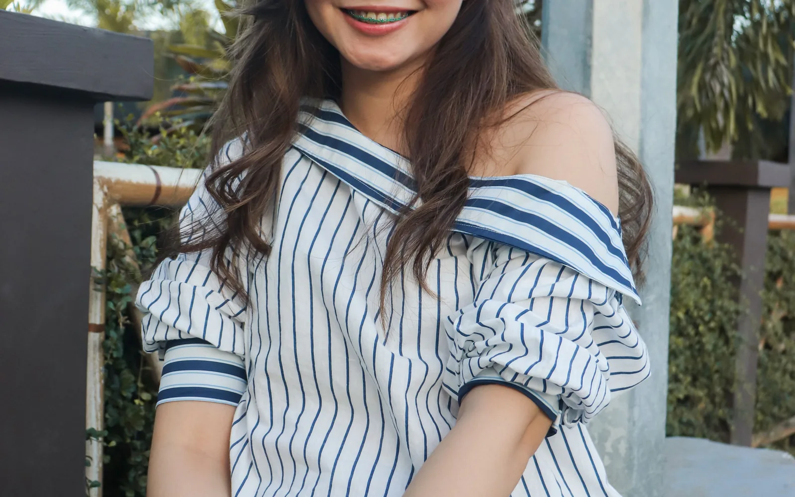 Young woman smiling outdoors with orthodontic braces