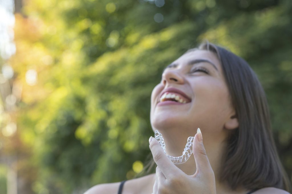 Beautiful smiling Turkish woman is holding an invisalign bracer